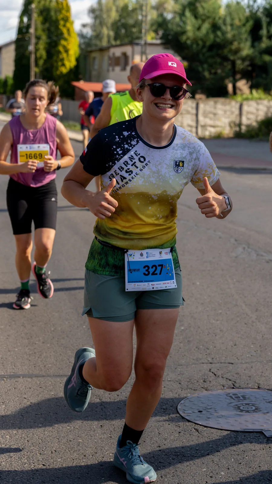 Kobieta i mężczyzna w koszulkach półmaratonu z Ratuszem w tle - Tarnogórski Półmaraton